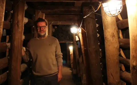 Mann in der Maschinenhalle Scherlbeck, umgeben von Holzverstrebungen und Grubenlampen.
