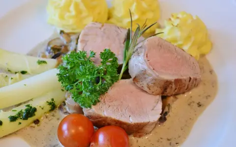 Zartes Schweinefilet mit Kartoffelröschen, Spargel und einer cremigen Sauce, serviert wie in einer alten Dorfbrennerei.