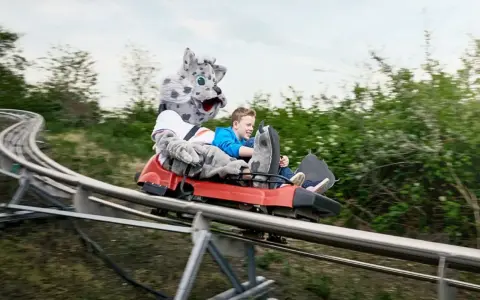 Junge mit Schneeleoparden-Maskottchen auf der Sommerrodelbahn Bottrop.