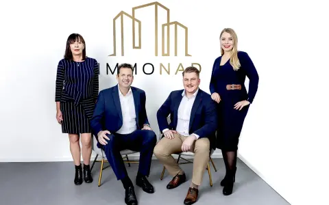 Immobilienpreise Oberhausen: Vier professionelle Makler des Unternehmens "MMONAD" posieren vor ihrem Logo.
