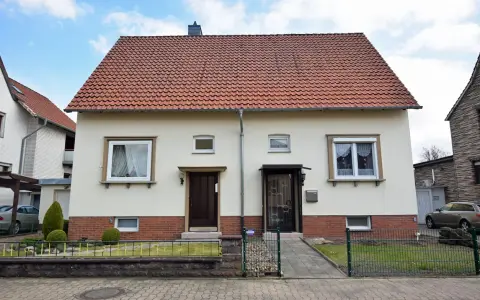 Zwei Eingänge an einem hellen Haus mit rotem Ziegeldach. Ein potenzielles Projekt für "altes Haus renovieren Kosten".