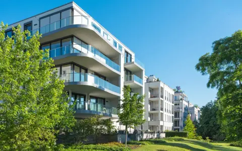 Moderne Wohngebäude mit Balkonen und Glasgeländern, umgeben von Grünflächen. Hier wird in Recklinghausen gebaut.