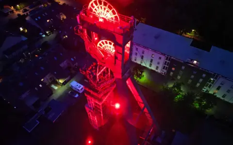 Der beleuchtete Förderturm des Erzschacht Marl erstrahlt in rotem Licht.