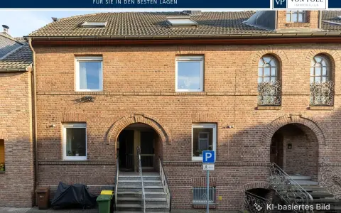 Ziegelhaus mit mehreren Fenstern und Eingängen. Ein Parkplatzschild weist auf die Lage hin, die für die Neuss Immobilienpreise relevant ist.