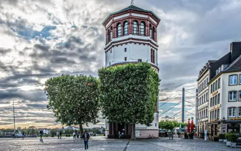Düsseldorfer Rheinturm mit Bäumen und Gebäuden. Die Immobilienpreise in Oberbilk sind ein Thema, das viele interessiert.