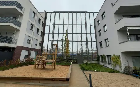 Moderne Wohnanlage mit Spielplatz und Sandkasten. Die Fassaden und Balkone sind hellgrau. Die Immobilienpreise in Leverkusen spiegeln die Attraktivität der Stadt wider.