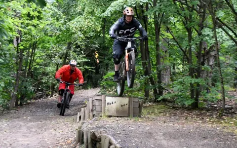 Zwei Mountainbiker springen über die Holzbox auf dem Halde Hoppenbruch Trail.