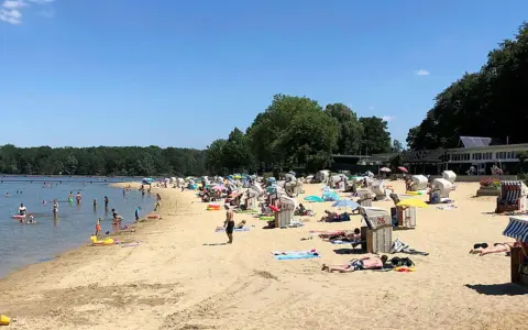 Sonniger Tag am **Haltern am See Strand** mit vielen Badegästen, Strandkörben und Bäumen im Hintergrund.