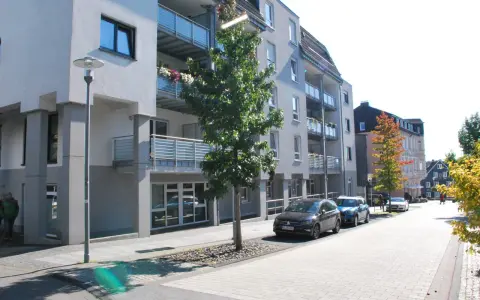 Moderne Wohngebäude mit Balkonen und Autos auf der Straße. Ein Baum steht vor einem Gebäude. Informationen zum Mietspiegel Wermelskirchen sind hier nicht ersichtlich.