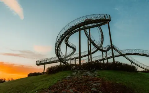 Die Achterbahn-Skulptur Tiger & Turtle auf einer Halde im Ruhrgebiet, im warmen Licht des Sonnenuntergangs.
