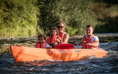 Familie genießt eine Fahrt im Kanu auf der Lippe, Kinder und Eltern mit Schwimmwesten.
