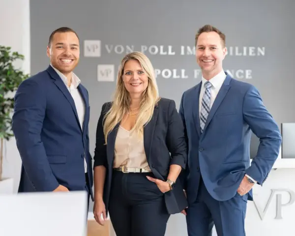 Drei Immobilienexperten lächeln vor dem Logo von Von Poll Immobilien. Sie kennen sich aus mit den Immobilienpreisen in Duisburg.