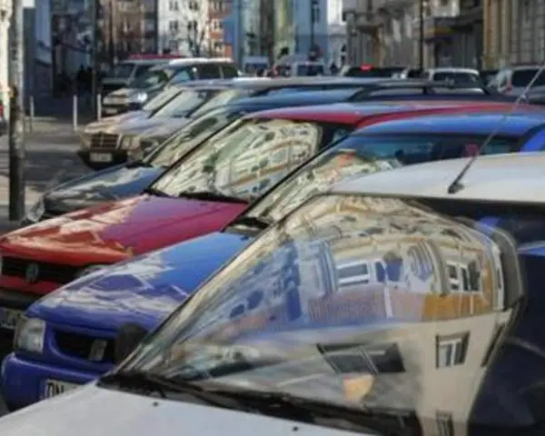 Autos parken in einer Reihe im Frankenberger Viertel Aachen. Menschen sitzen an einem Tisch im Hintergrund.