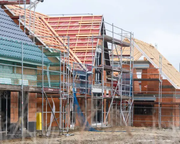 Neubau-Reihenhäuser in Moers im Rohbau, Gerüste umgeben die Ziegelbauten. Die steigenden immobilienpreise moers spiegeln sich in solchen Projekten wider.