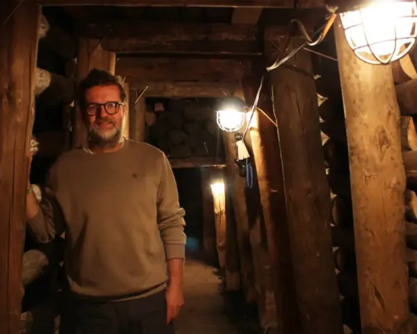 Mann in der Maschinenhalle Scherlbeck, umgeben von Holzverstrebungen und Grubenlampen.
