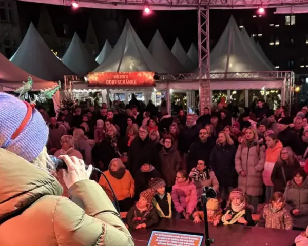 Menschenmenge auf dem Castrop Rauxel Weihnachtsmarkt vor der Dorfkneipe, eine Frau singt ins Mikrofon.