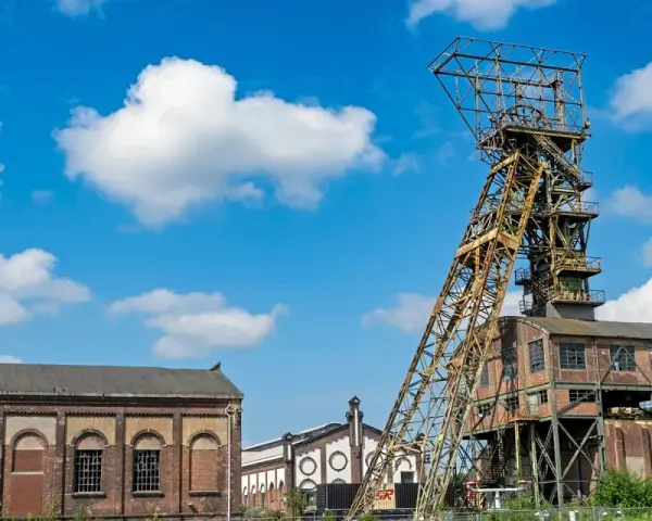 Das Förderturmgerüst der Zeche Ewald in Oer-Erkenschwick ragt unter blauem Himmel mit Wolken empor.