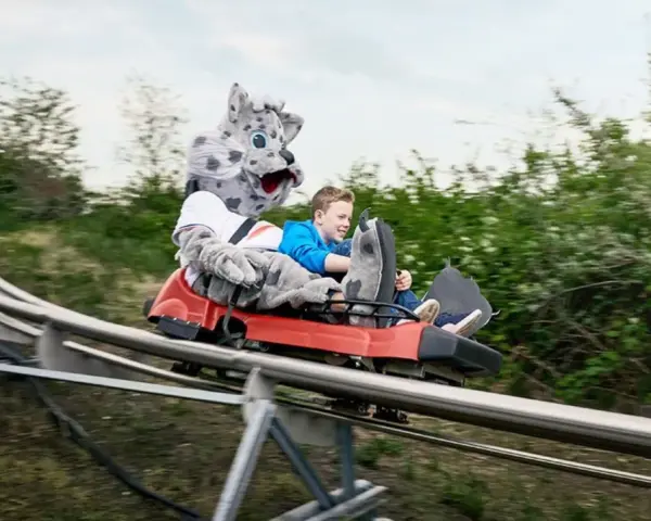 Junge mit Schneeleoparden-Maskottchen auf der Sommerrodelbahn Bottrop.