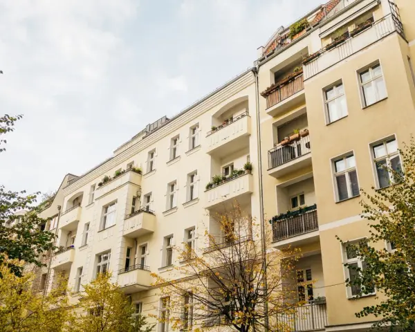 Gelbe Mehrfamilienhäuser mit Balkonen und Bäumen im Herbst. Ein Blick auf die Mietpreise im Rhein-Sieg-Kreis.