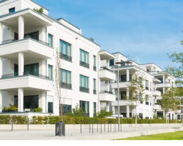 Moderne weiße Wohnanlage mit Balkonen und Bäumen. Ein Blick auf den Quadratmeterpreis Eigentumswohnung in dieser Gegend.