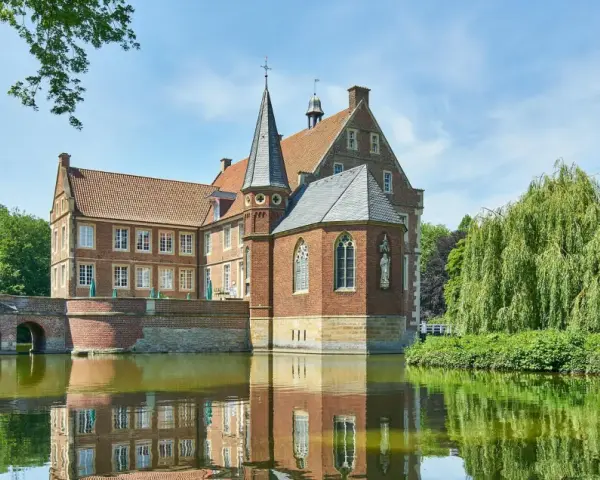 Wasserschloss in Haltern am See, umgeben von einem Wassergraben und üppiger Vegetation.