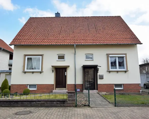 Zwei Eingänge an einem hellen Haus mit rotem Ziegeldach. Ein potenzielles Projekt für "altes Haus renovieren Kosten".