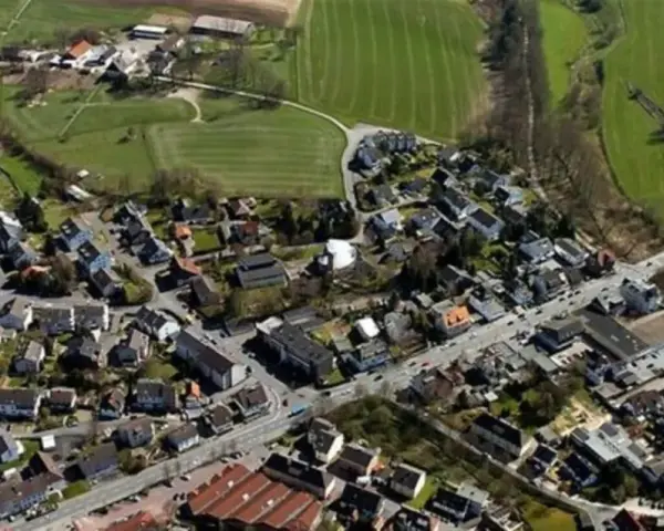 Luftaufnahme eines Dorfes mit Häusern, Straßen und Feldern.