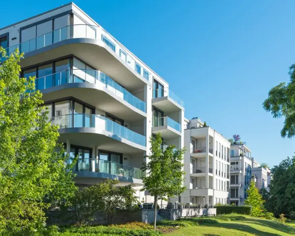 Moderne Wohngebäude mit Balkonen und Glasgeländern, umgeben von Grünflächen. Hier wird in Recklinghausen gebaut.