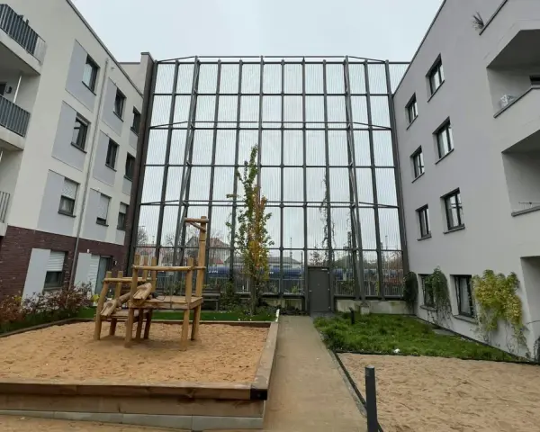 Moderne Wohnanlage mit Spielplatz und Sandkasten. Die Fassaden und Balkone sind hellgrau. Die Immobilienpreise in Leverkusen spiegeln die Attraktivität der Stadt wider.