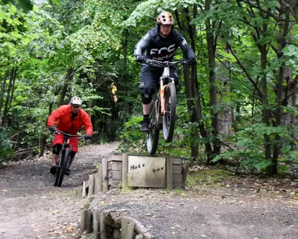 Zwei Mountainbiker springen über die Holzbox auf dem Halde Hoppenbruch Trail.