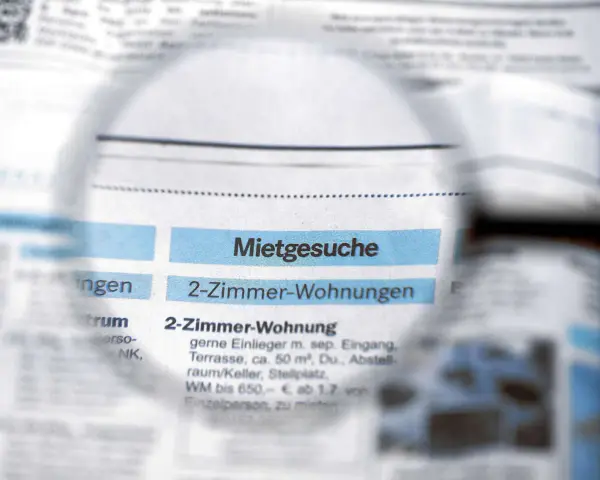 Lupe über Zeitungsanzeigen mit "Mietgesuche" und "2-Zimmer-Wohnungen". Ein Blick auf den Mietspiegel Moers.