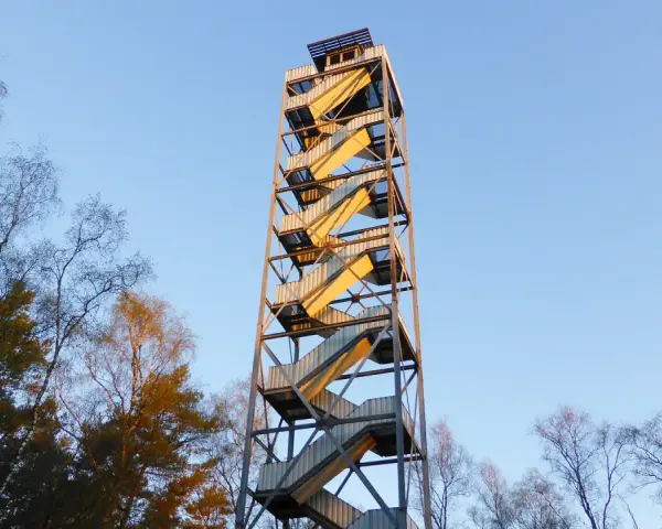 Der feuerwachturm Hohe Mark ragt mit seinen gewendelten Treppen in den blauen Himmel. Umgeben von kahlen Bäumen, verspricht er eine weite Aussicht.