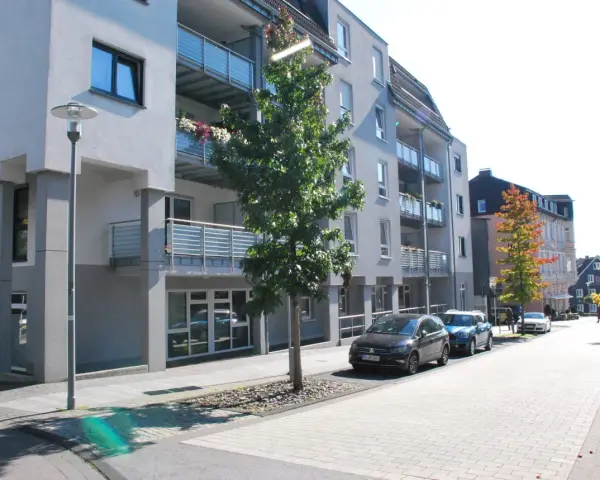 Moderne Wohngebäude mit Balkonen und Autos auf der Straße. Ein Baum steht vor einem Gebäude. Informationen zum Mietspiegel Wermelskirchen sind hier nicht ersichtlich.