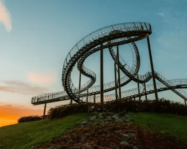 Die Achterbahn-Skulptur Tiger & Turtle auf einer Halde im Ruhrgebiet, im warmen Licht des Sonnenuntergangs.