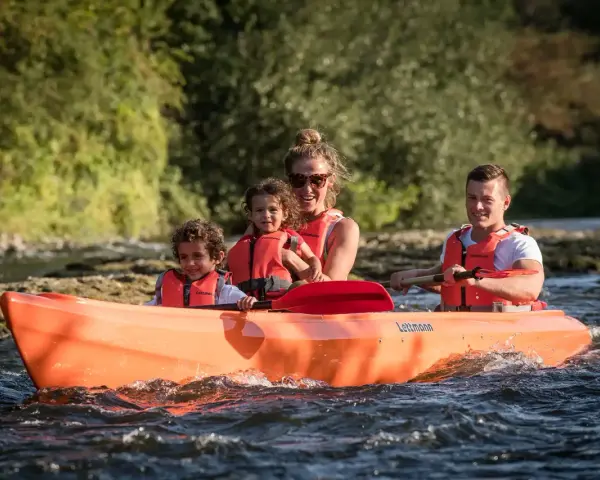 Familie genießt eine Fahrt im Kanu auf der Lippe, Kinder und Eltern mit Schwimmwesten.
