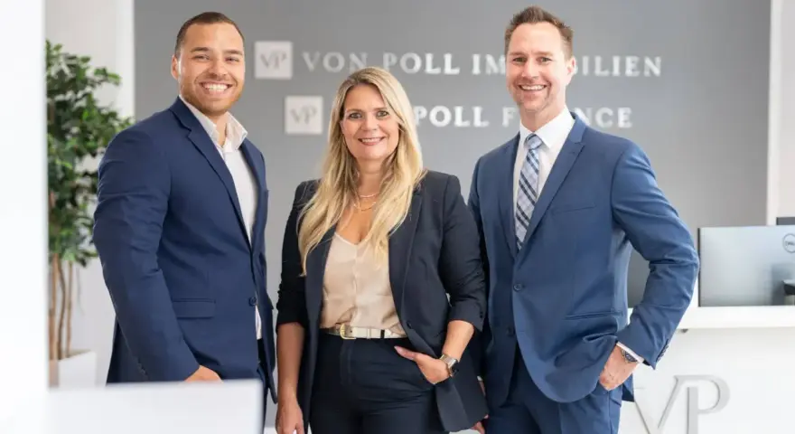 Drei Immobilienexperten lächeln vor dem Logo von Von Poll Immobilien. Sie kennen sich aus mit den Immobilienpreisen in Duisburg.