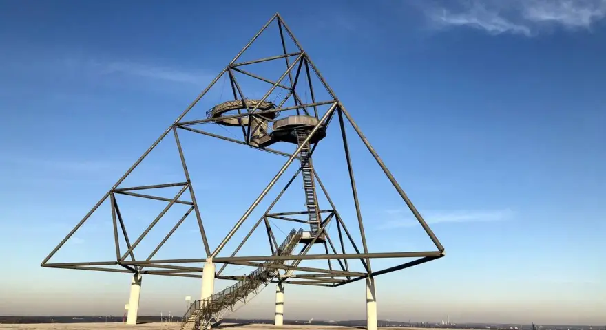 Das Tetraeder auf der Halde Beckstraße in Bottrop, ein Wahrzeichen der Industriekultur, ragt gegen einen blauen Himmel.