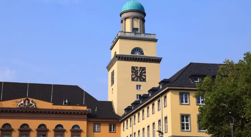 Gelber Turm mit Uhr und historischen Gebäuden in Witten. Die Immobilienpreise in Witten sind hier ein Thema.