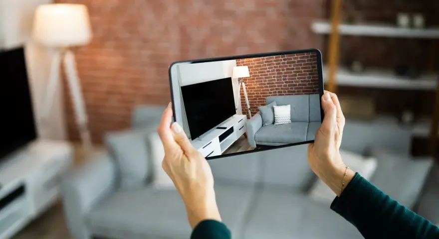Hände halten Smartphone, das eine Wohnung mit Sofa und Fernseher zeigt. Darf ein Makler Fotos von meiner Wohnung machen? Ja, für die Vermarktung.