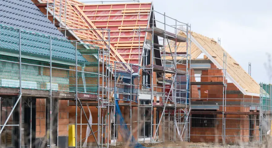 Neubau-Reihenhäuser in Moers im Rohbau, Gerüste umgeben die Ziegelbauten. Die steigenden immobilienpreise moers spiegeln sich in solchen Projekten wider.