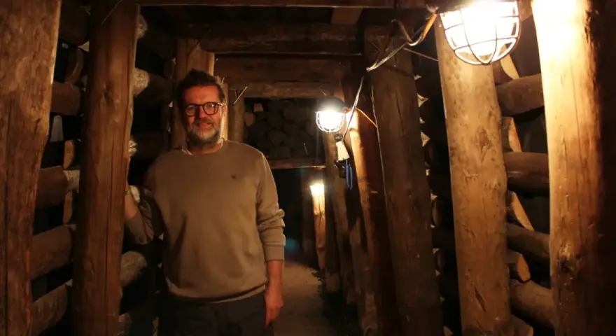 Mann in der Maschinenhalle Scherlbeck, umgeben von Holzverstrebungen und Grubenlampen.