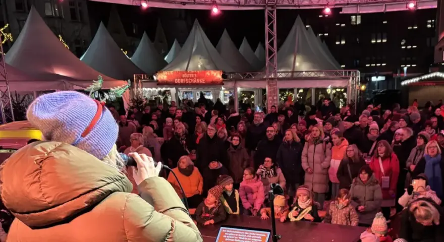 Menschenmenge auf dem Castrop Rauxel Weihnachtsmarkt vor der Dorfkneipe, eine Frau singt ins Mikrofon.