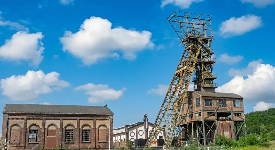 Das Förderturmgerüst der Zeche Ewald in Oer-Erkenschwick ragt unter blauem Himmel mit Wolken empor.