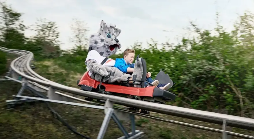 Junge mit Schneeleoparden-Maskottchen auf der Sommerrodelbahn Bottrop.