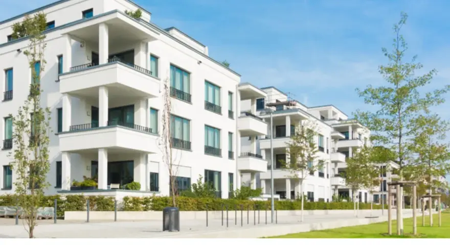 Moderne weiße Wohnanlage mit Balkonen und Bäumen. Ein Blick auf den Quadratmeterpreis Eigentumswohnung in dieser Gegend.