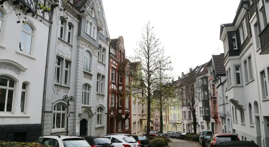 Reihenhäuser in Solingen, die einen Eindruck vom Mietspiegel vermitteln. Autos parken in der Straße.