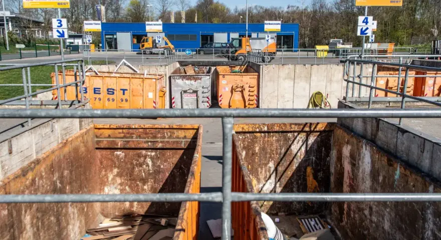 Große orange Container auf einem Recyclinghof in Bottrop. Ein kleiner gelber Bagger steht bereit.