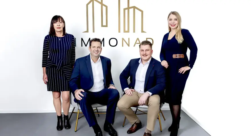 Immobilienpreise Oberhausen: Vier professionelle Makler des Unternehmens "MMONAD" posieren vor ihrem Logo.