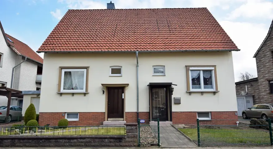 Zwei Eingänge an einem hellen Haus mit rotem Ziegeldach. Ein potenzielles Projekt für "altes Haus renovieren Kosten".