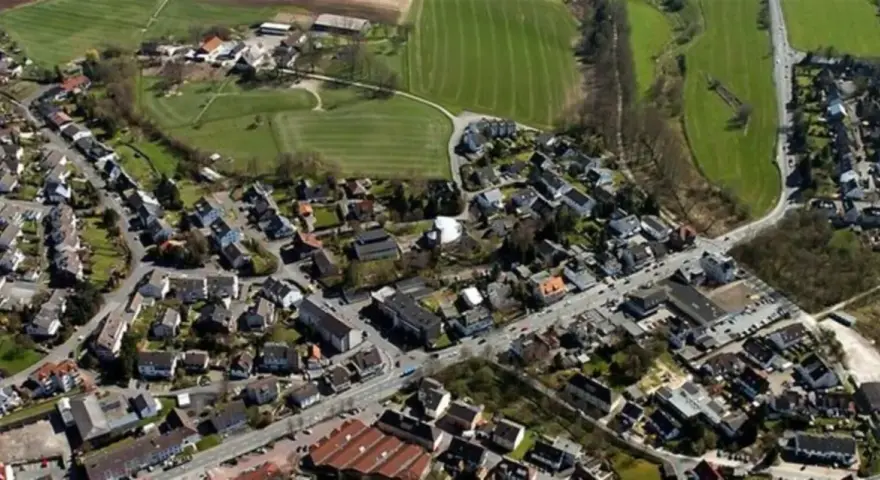 Luftaufnahme eines Dorfes mit Häusern, Straßen und Feldern.